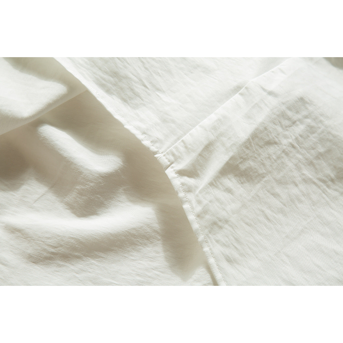 Close-up of ivory shirt fabric and a stitched seam with soft folds.