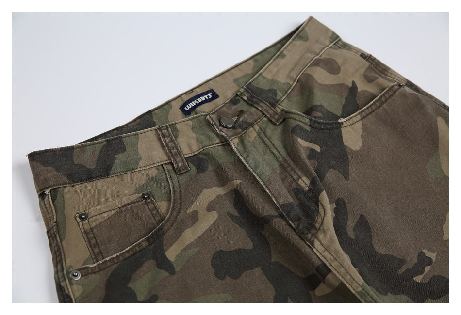 Cropped flat-lay view of the front waist and upper legs of olive, brown and black camouflage trousers.