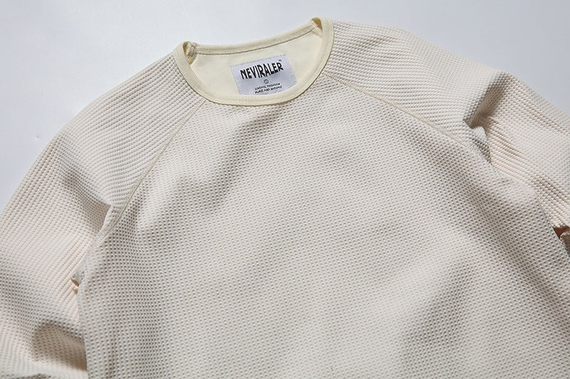Close-up of the cream waffle-knit shirt's front texture, raglan seams, and crew neckline.
