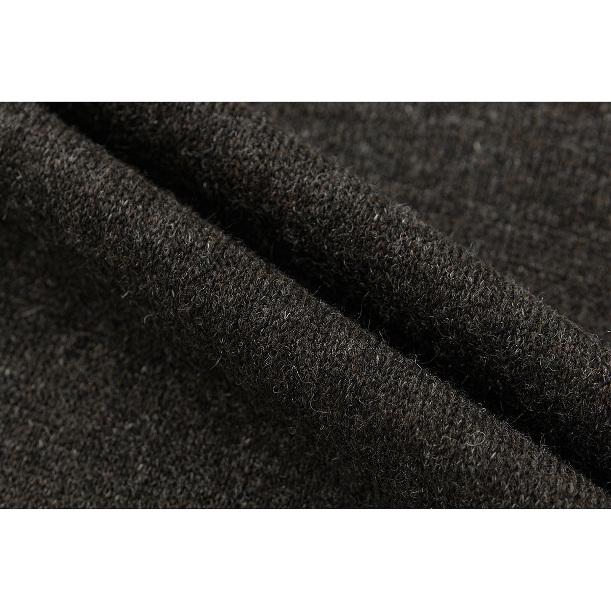 Macro view of a seam and folded edge on dark heathered fabric.