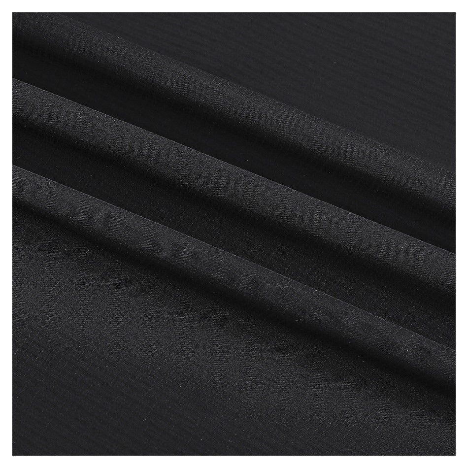 Close-up of black fabric arranged in soft folds, showing its subtle surface texture.