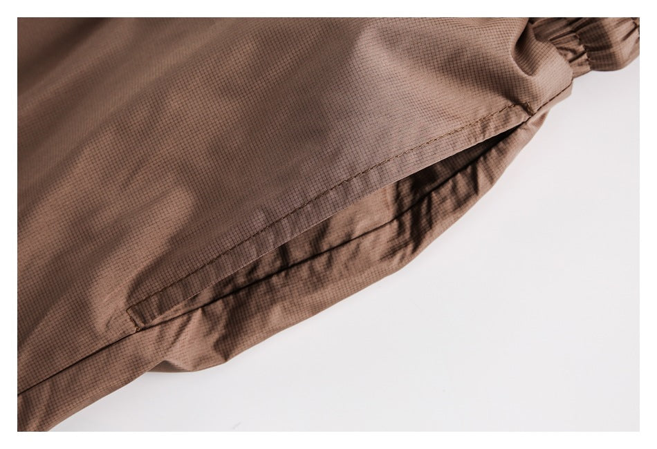 Close-up of brown shorts with a stitched seam and gathered fabric along the edge.