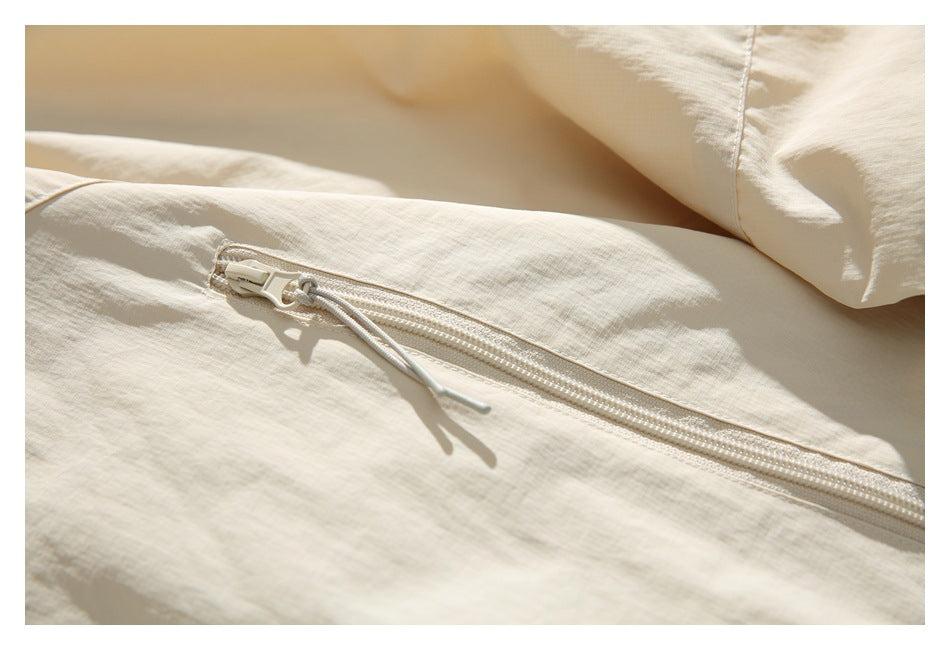 Close-up of a zipper pocket on the ivory jacket, showing its corded pull and stitching.