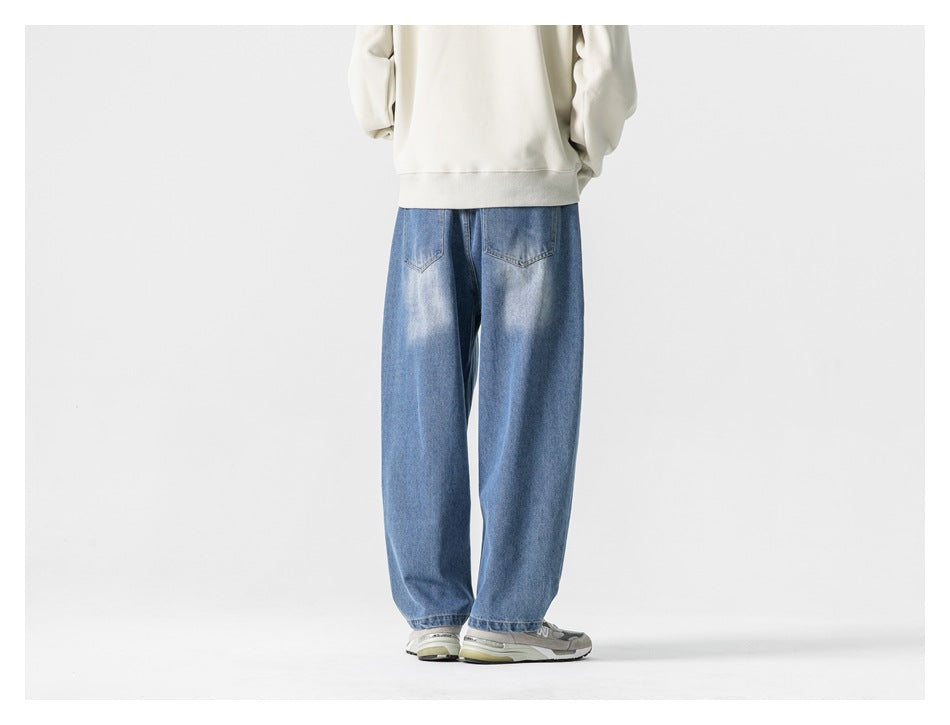 Full-length back view of a model wearing loose blue jeans and a cream sweatshirt.