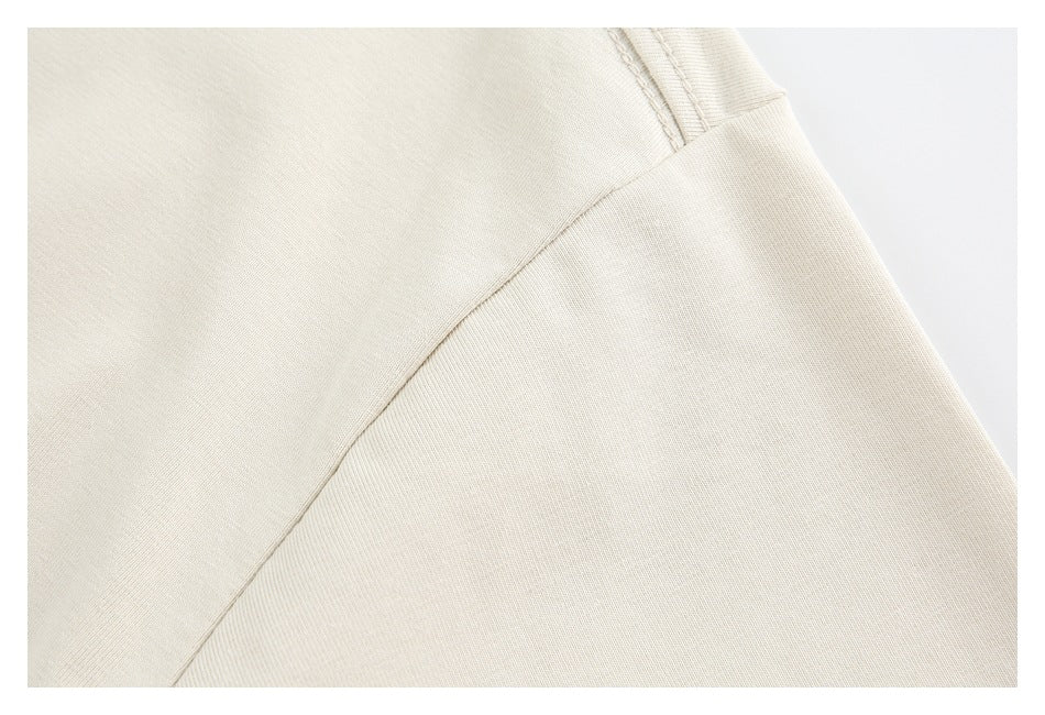 Close-up of cream fabric showing a curved seam and stitching.