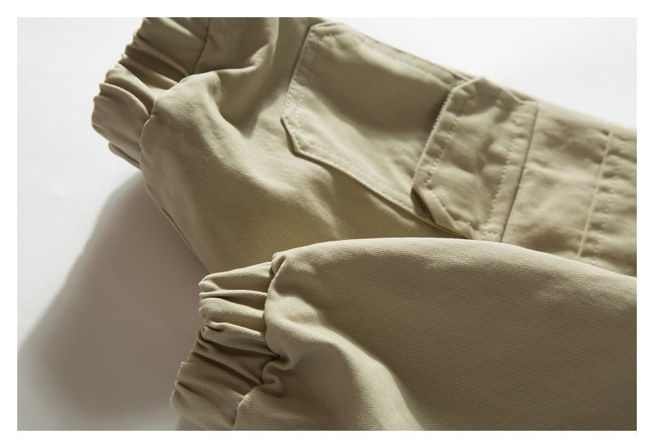 Folded beige garment detail showing a flap pocket and gathered elastic cuffs.