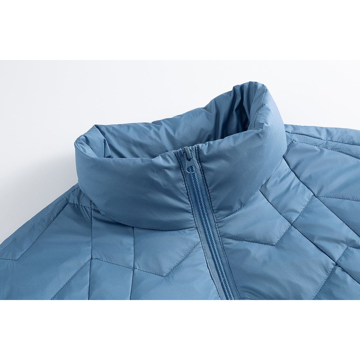 Close-up of a blue quilted jacket showing its tall stand collar, front zipper, and geometric stitching.