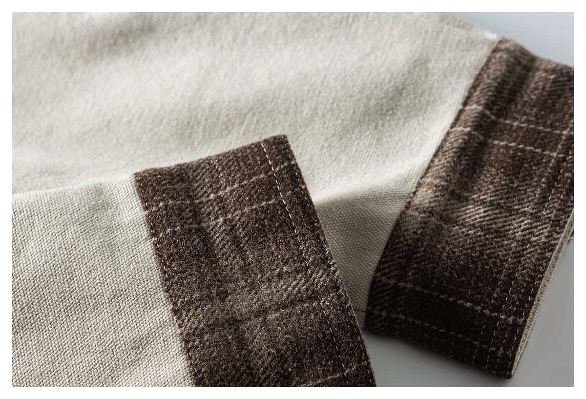 Close-up of beige woven fabric with dark brown plaid trim and visible stitching.