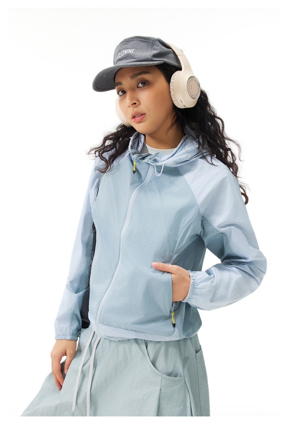 Closer view of a model wearing a light blue hooded zip jacket with elastic cuffs and front pockets.