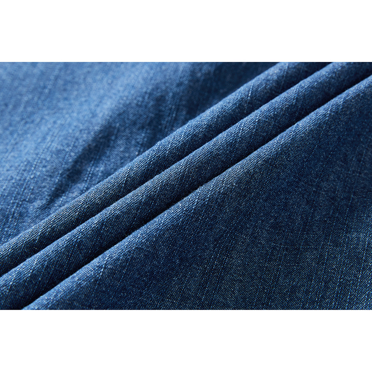 Macro view of blue denim fabric arranged in diagonal folds.