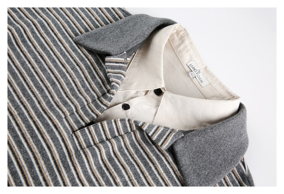 Close-up of a striped knit polo collar, gray collar trim, cream shirt collar and black buttons.