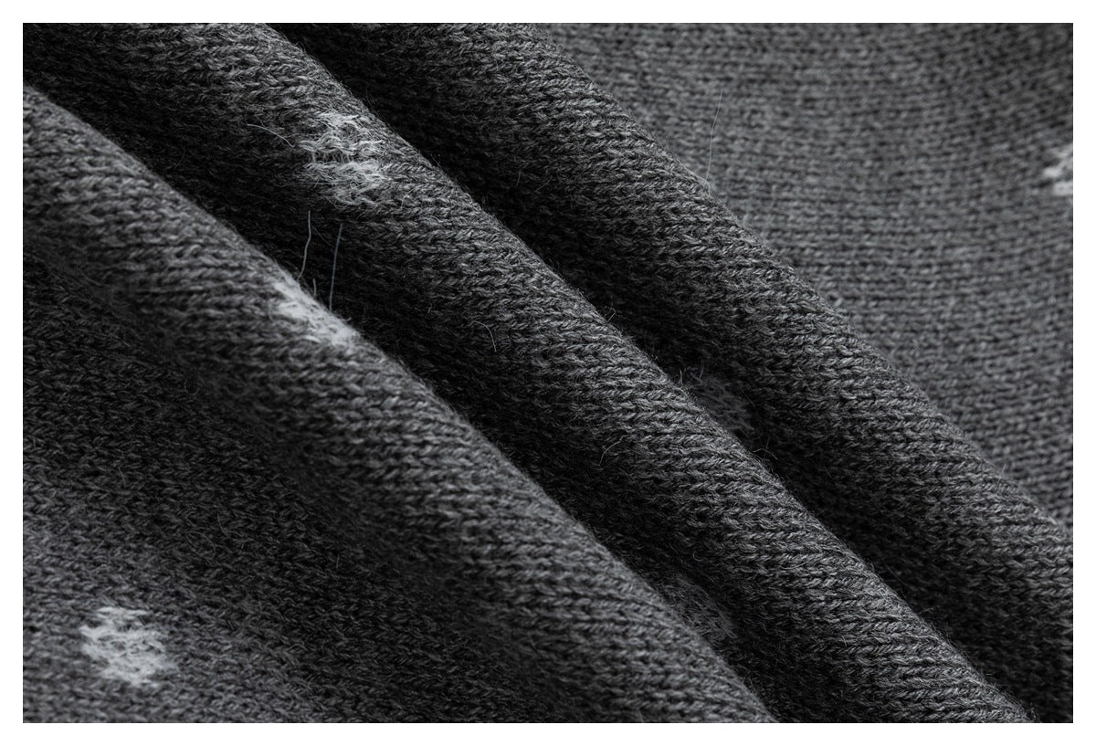 Close-up of dark gray knitted fabric with a visible yarn texture and a few light-colored fibers.