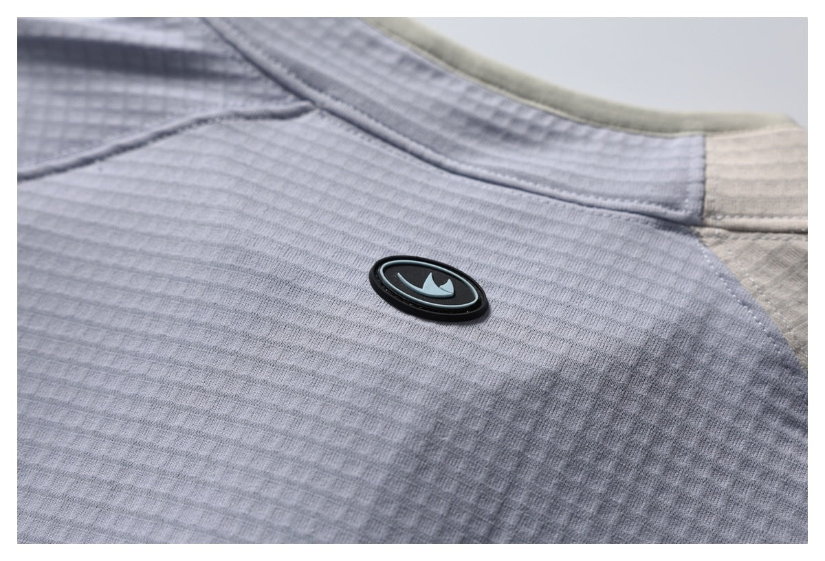 Close-up of gray textured garment fabric with an oval emblem and an off-white contrasting panel.