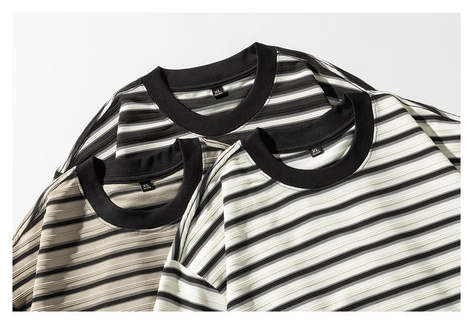 Three striped crew-neck shirts in beige, black, and off-white colorways, arranged together.