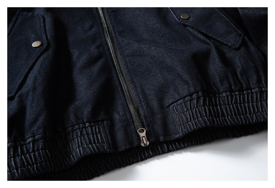 Close-up of a dark indigo jacket front with a zipper, snap-flap pockets, and a gathered elastic hem.