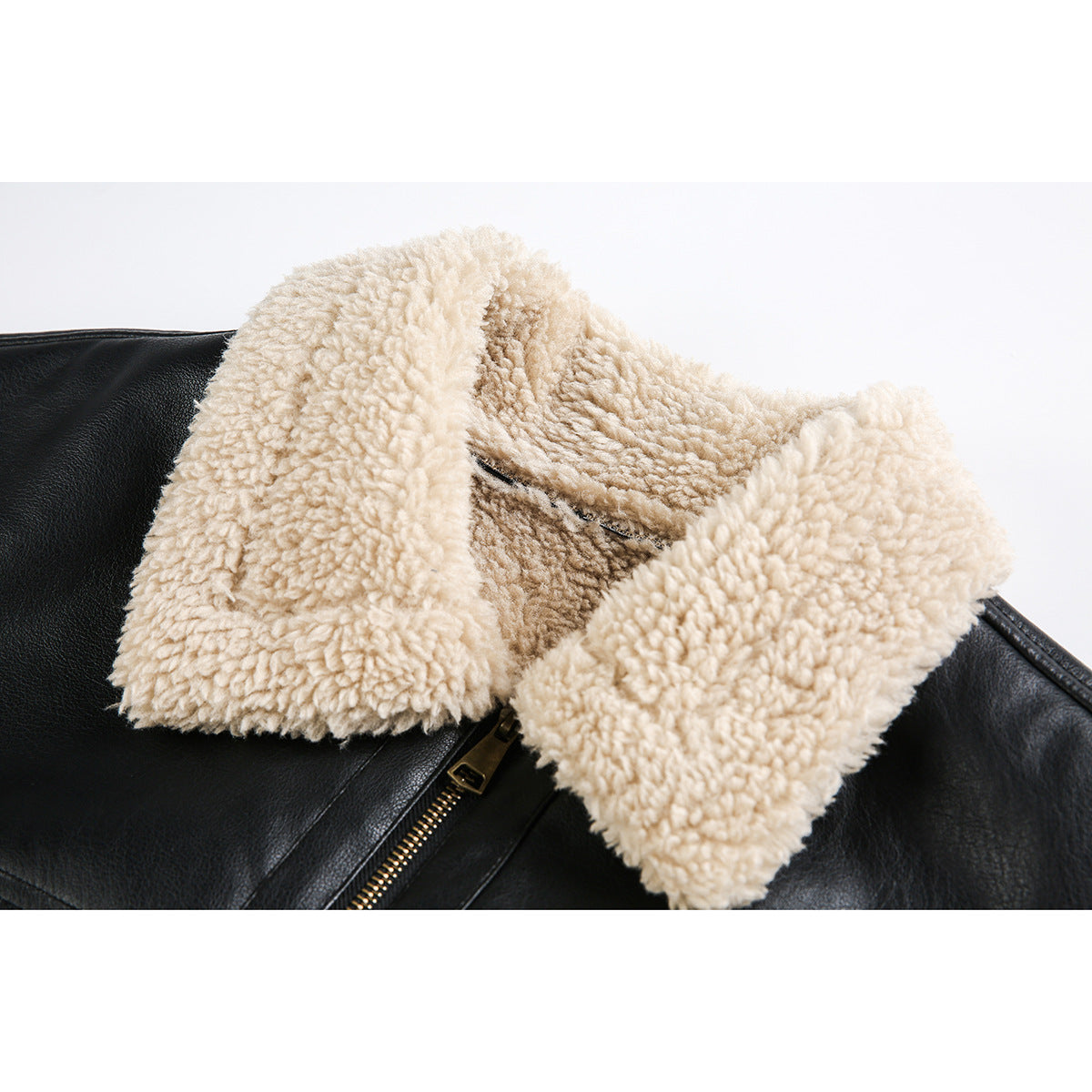Close-up of a black jacket with a thick cream sherpa collar and brass-tone front zipper.