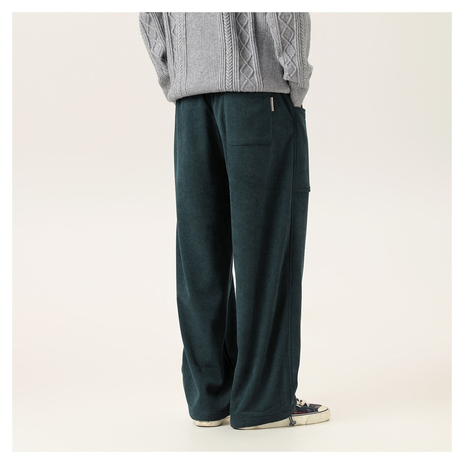 Rear view of a model wearing dark teal wide-leg pants with back and side pockets.