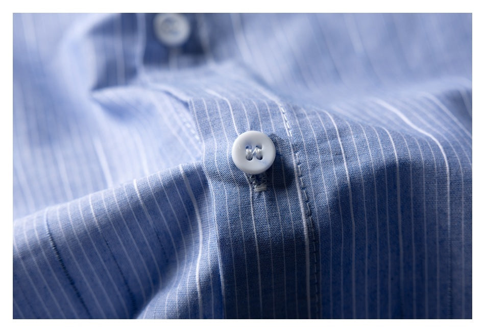Close-up of a white button and buttonhole on the blue shirt's fine white-striped placket.