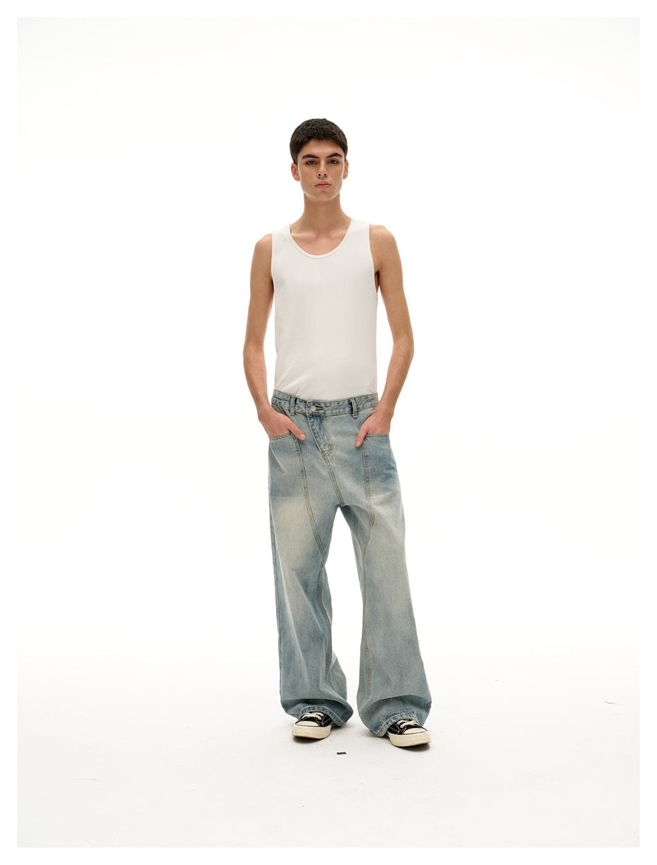 Full-length front view of a model wearing a white tank top and oversized light-wash jeans with black-and-white sneakers.