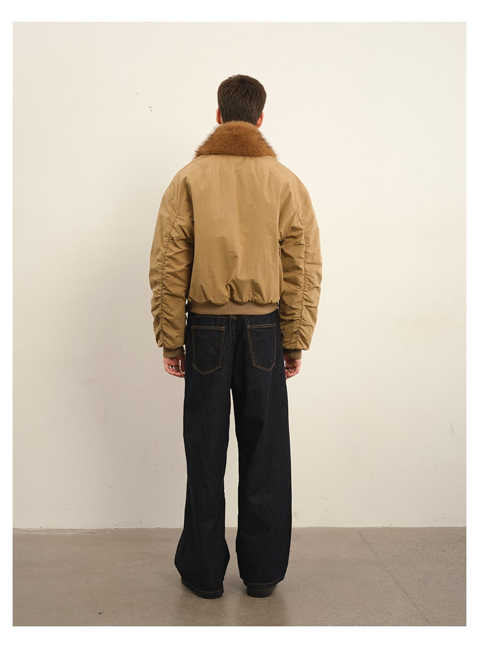 Back view of a man wearing a khaki cropped jacket with brown faux-fur collar, ruched sleeves and wide dark jeans
