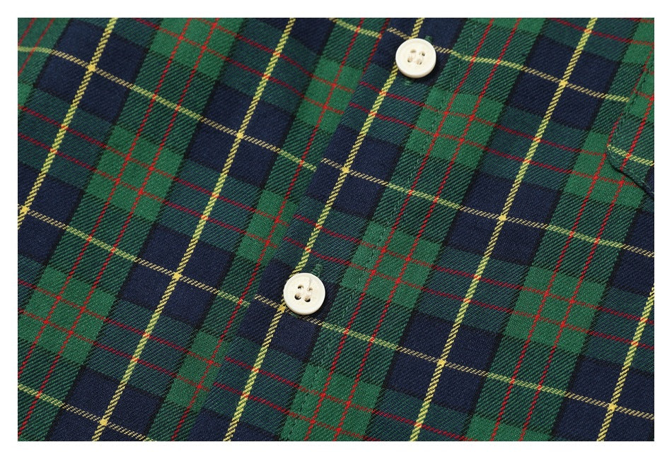 Close-up of two cream buttons on the green and navy tartan shirt front.
