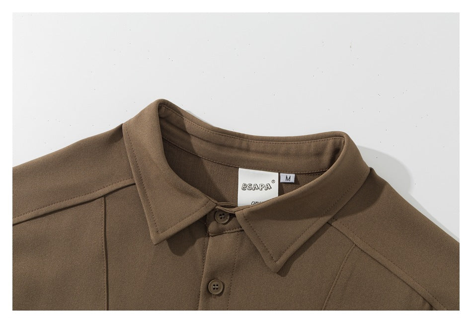 Close-up of a brown shirt's pointed collar, shoulder seams, front buttons, and inner size label.