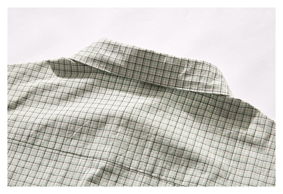 Close-up of the back yoke and collar of a pale green and white plaid shirt.