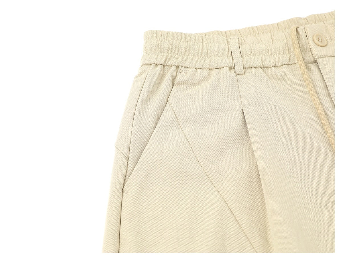 Close-up of the cream trousers' elastic waistband, belt loop, side pocket opening and drawstring.