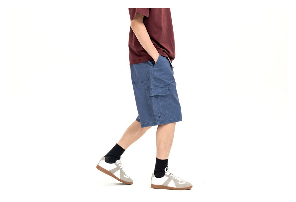 Side view of a model wearing blue cargo shorts with a flap pocket and burgundy T-shirt.