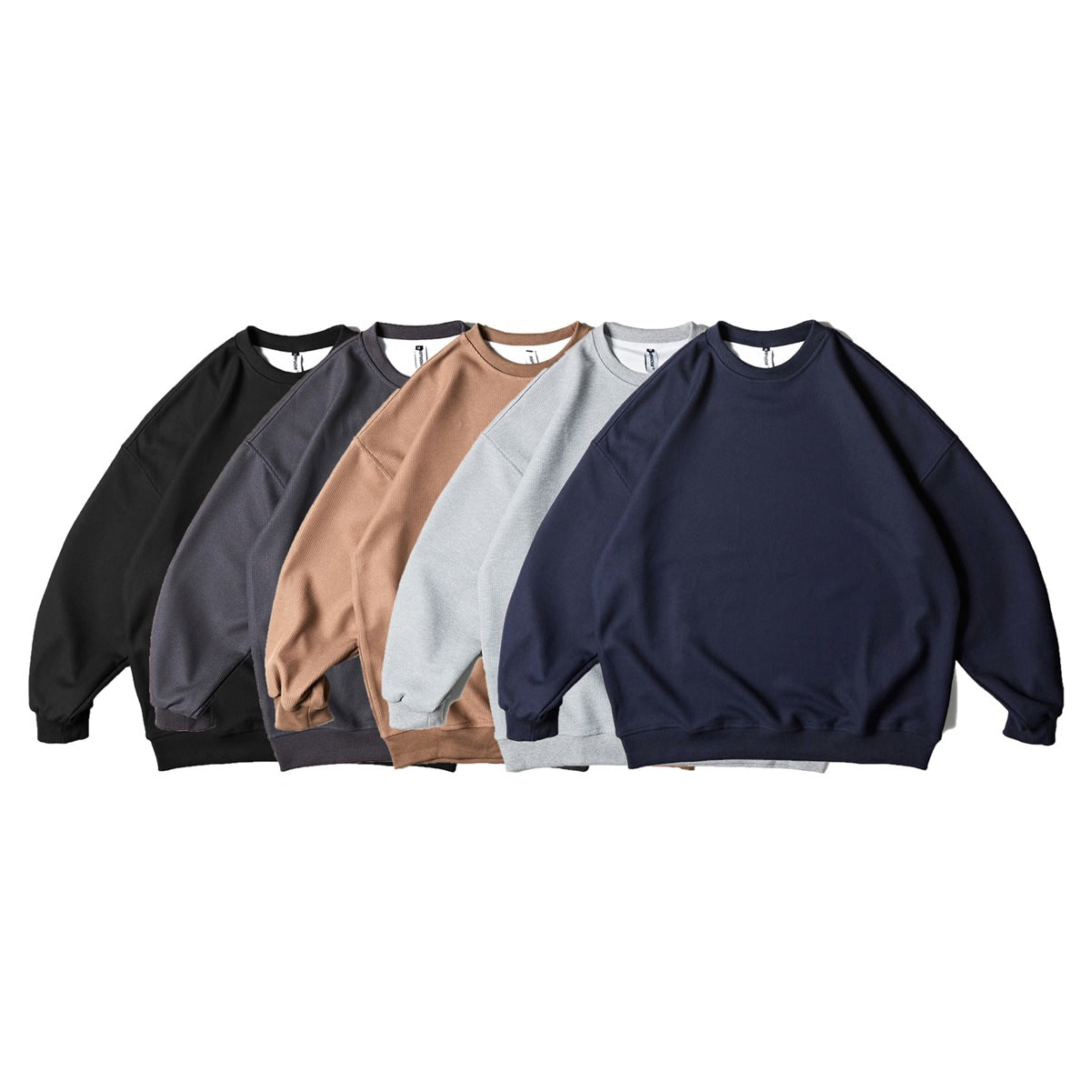Five plain crewneck sweatshirts arranged together in black, charcoal, tan, light gray, and navy.