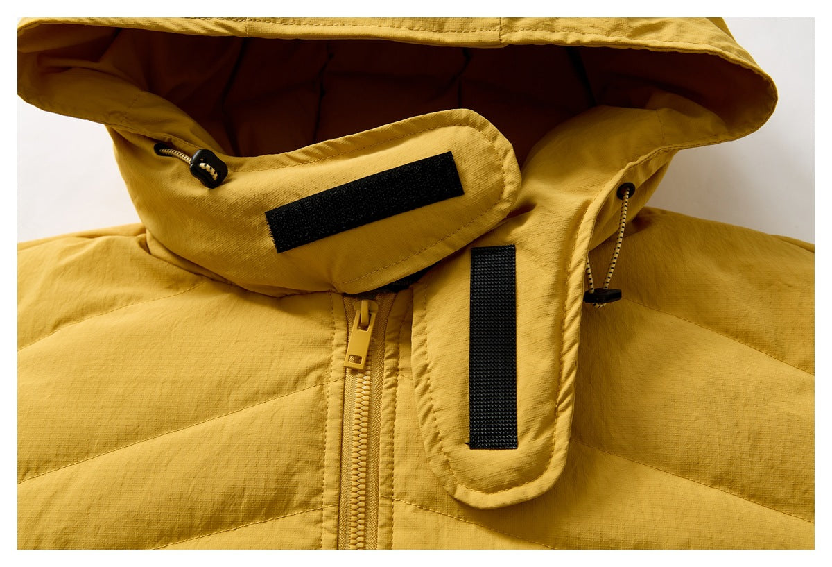 Close-up of a mustard yellow quilted jacket hood with drawcords, zipper and black hook-and-loop tabs.