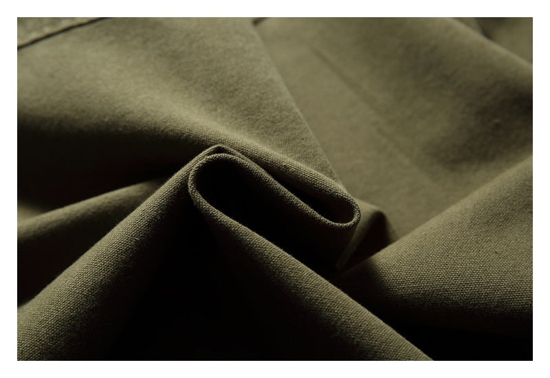 Close-up of olive fabric gathered into folds, showing its surface texture.