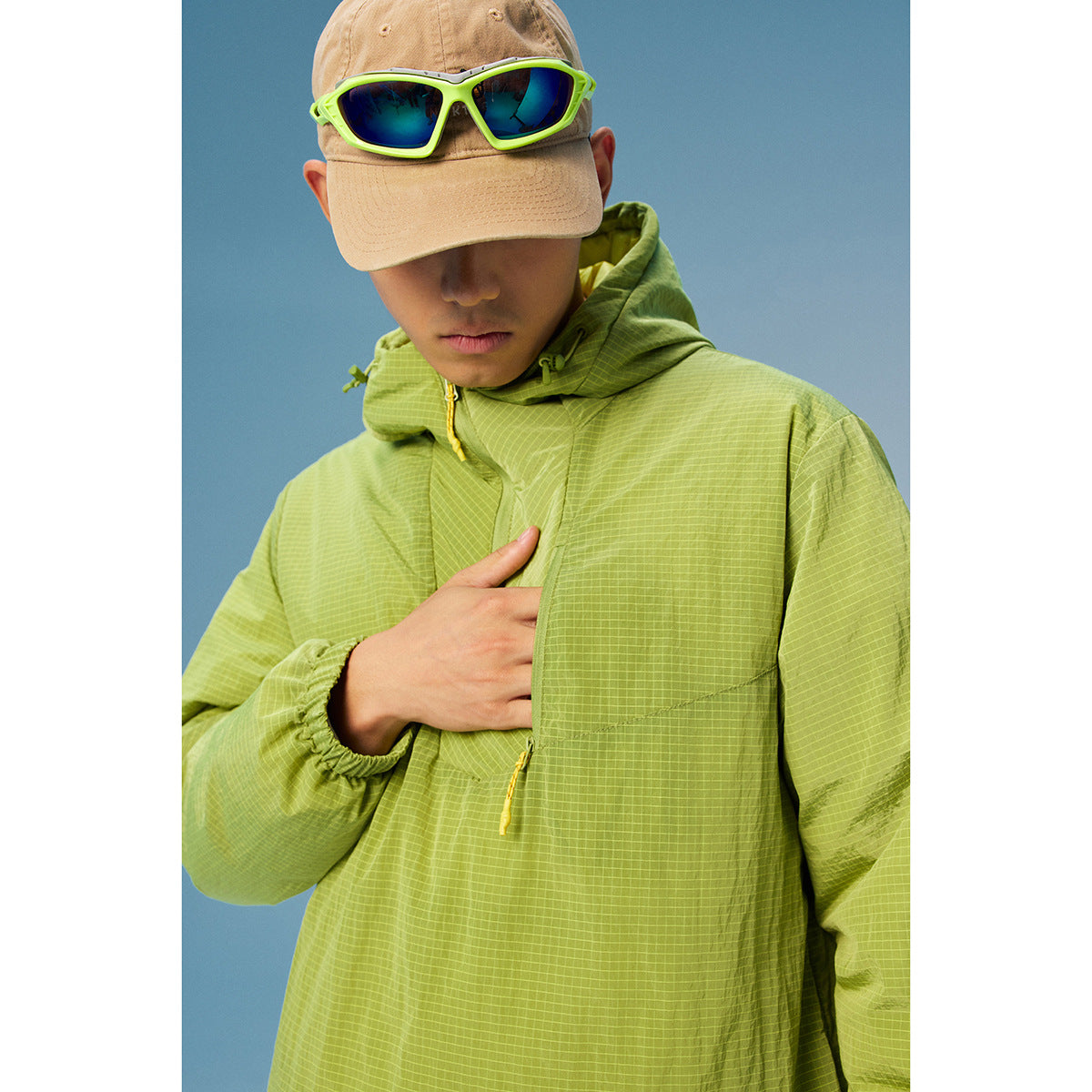 Close-up of a lime-green grid-pattern hooded pullover with yellow zipper pulls.