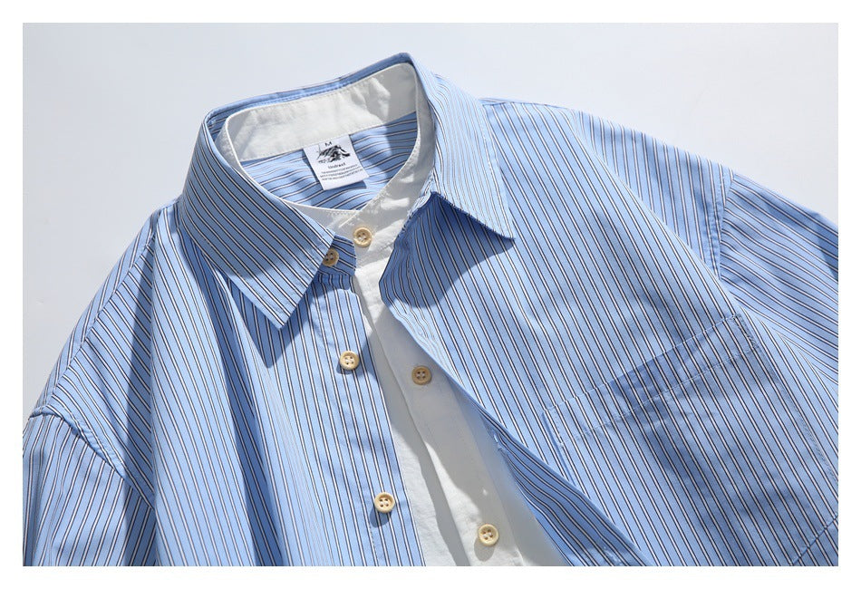Light blue striped button-up shirt laid flat, showing its pointed collar, white inner placket, and tan buttons.
