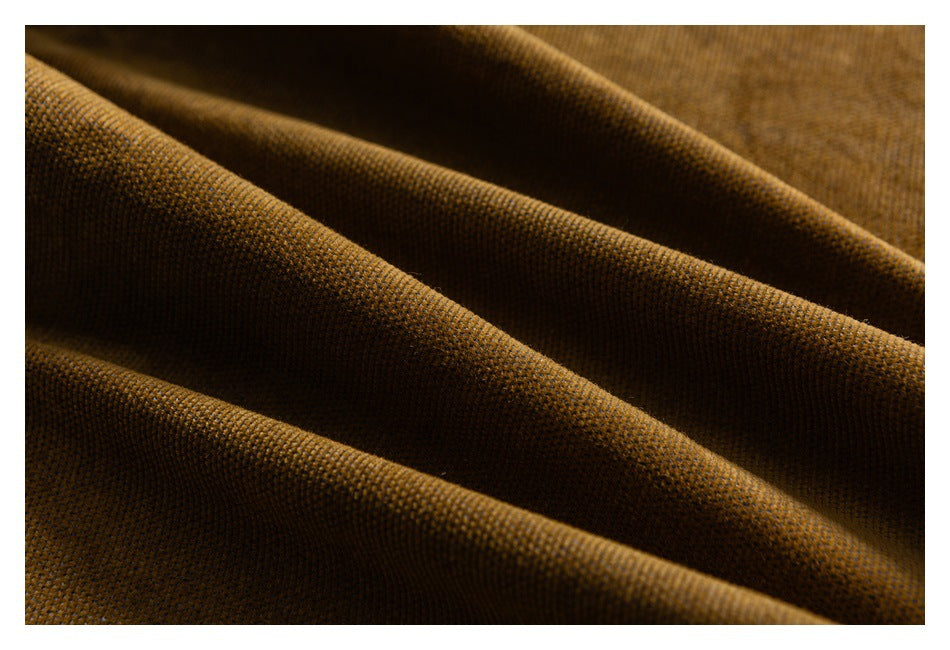 Macro view of mustard-brown fabric draped in folds, showing its woven texture.