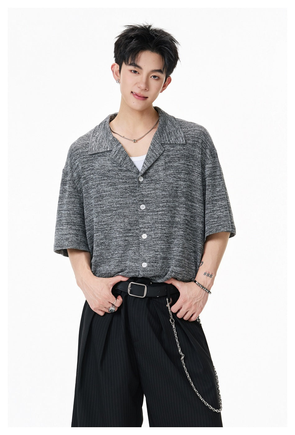 Model wearing a dark gray marled short-sleeve button-up shirt with a wide open collar and white buttons.