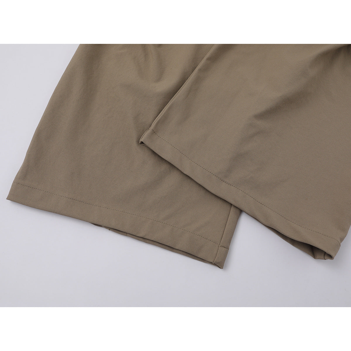 Close-up of taupe trousers showing the wide legs and stitched hems.