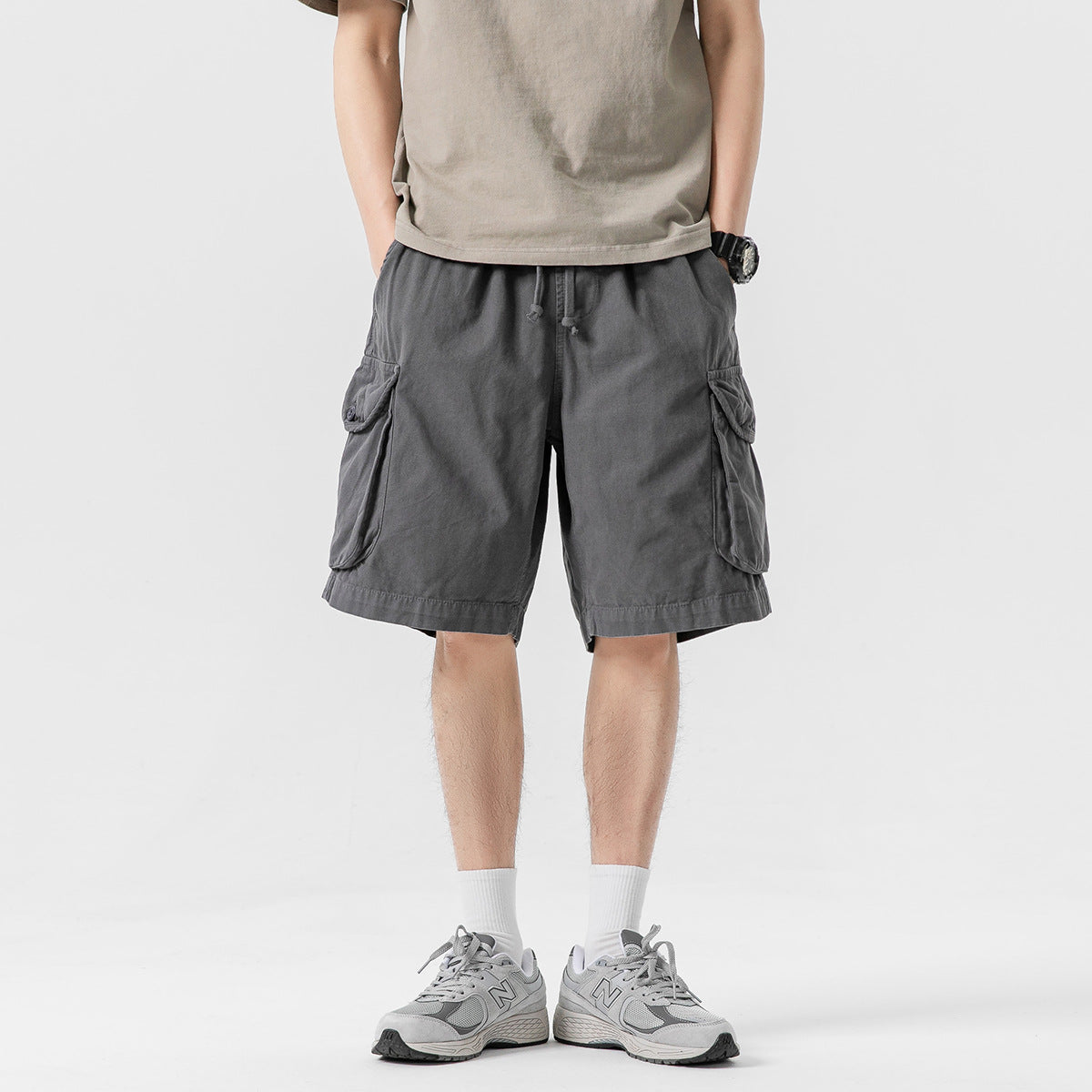Model wearing charcoal gray cargo shorts with an elastic drawstring waist and large flap pockets, shown from the front.
