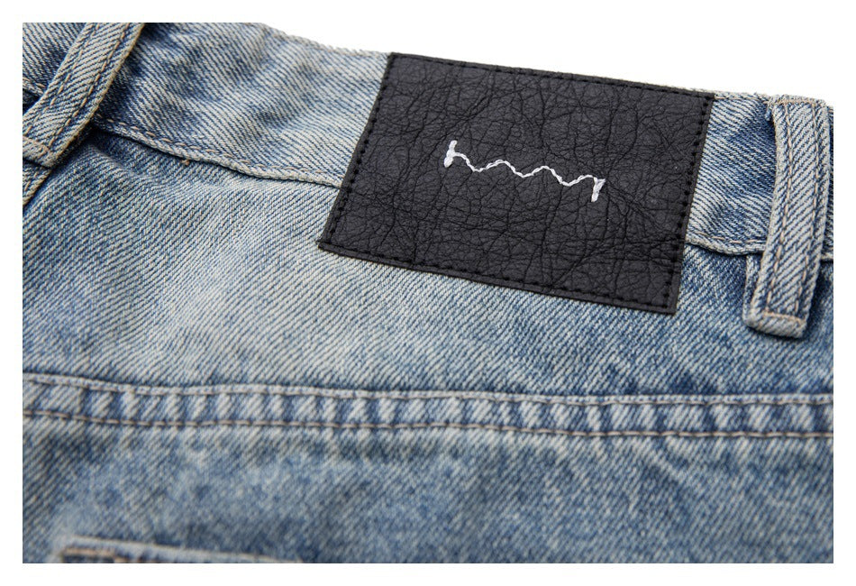 Close-up of the jeans' black waistband patch with a white embroidered squiggle.