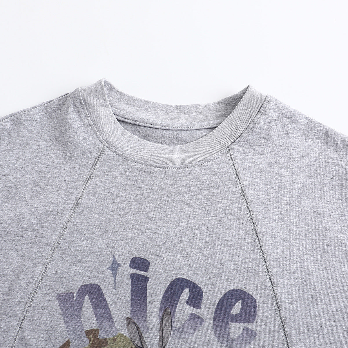 Close-up of a heather-gray crew-neck T-shirt with raglan seams and part of a colorful chest graphic.