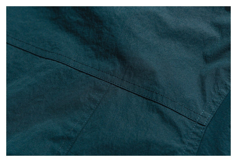 Close-up of dark teal garment fabric and diagonal stitched seams.