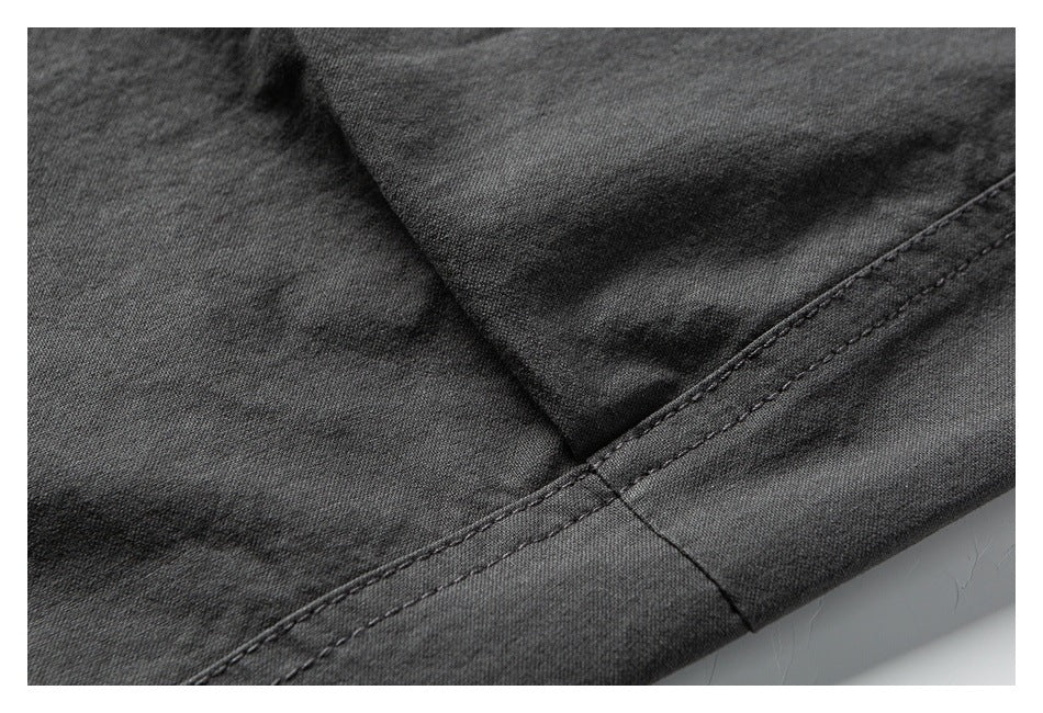 Close-up of charcoal-black garment fabric with a diagonal double-stitched hem seam.