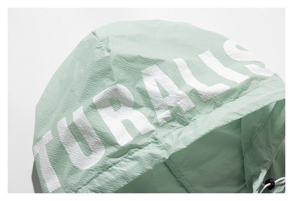 Close-up of a pale mint jacket hood with large white lettering and an adjustable drawcord.