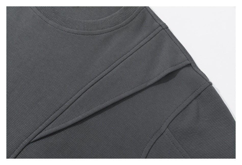 Close-up of a charcoal crewneck sweatshirt showing the ribbed collar and layered shoulder seams.