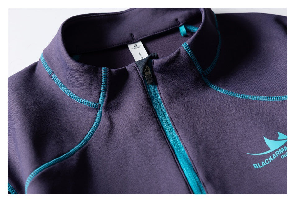 Close-up of the purple top's high collar, teal-trimmed zipper, contrast stitching, and partial teal chest print.