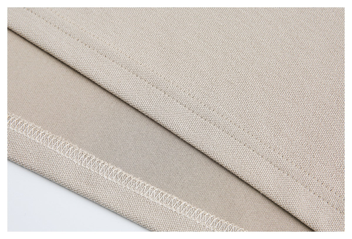 Close-up of beige garment fabric showing the folded hem and overlock stitching.