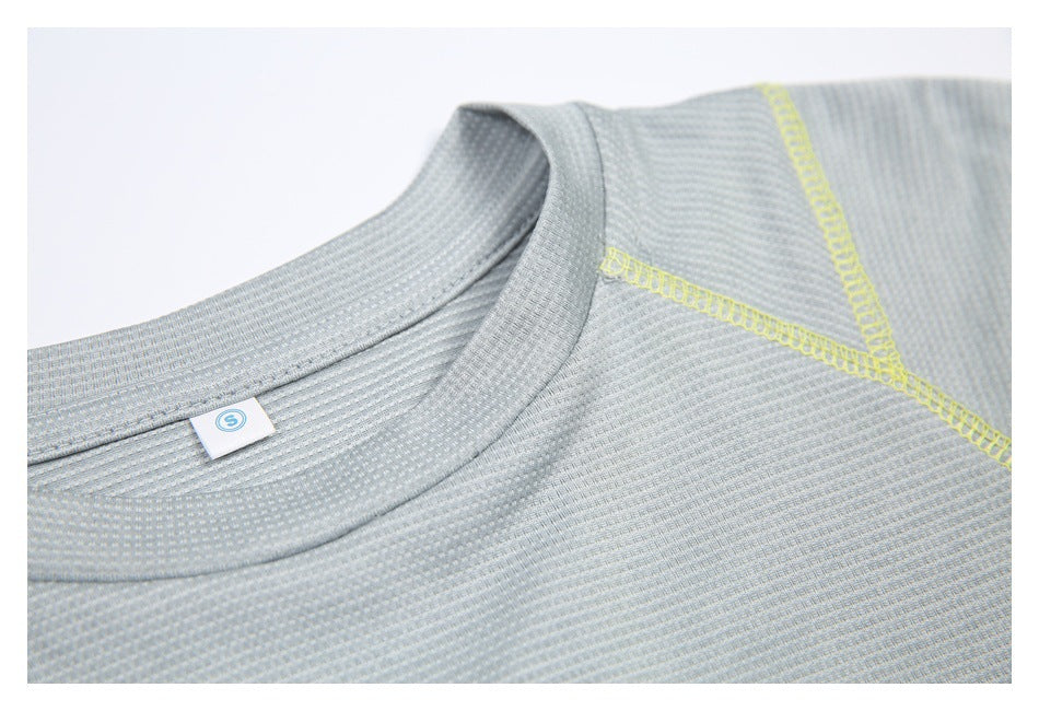 Close-up of a pale gray textured shirt neckline with bright yellow seam stitching and a small neck tag.