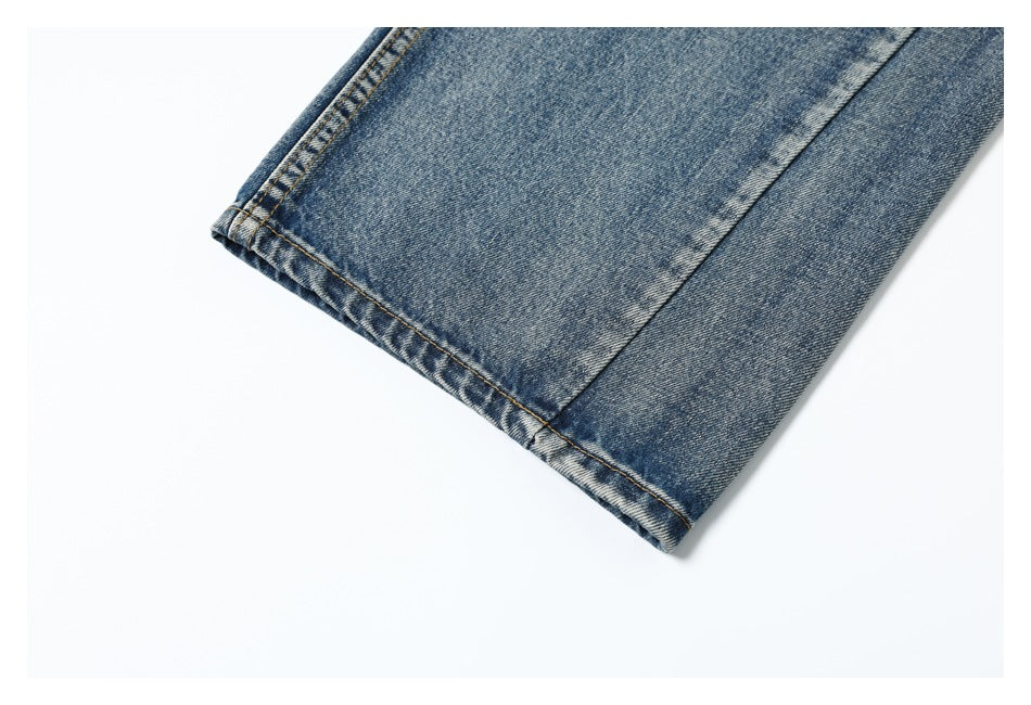 Close-up of the stitched hem of a blue denim jeans leg against a white background.