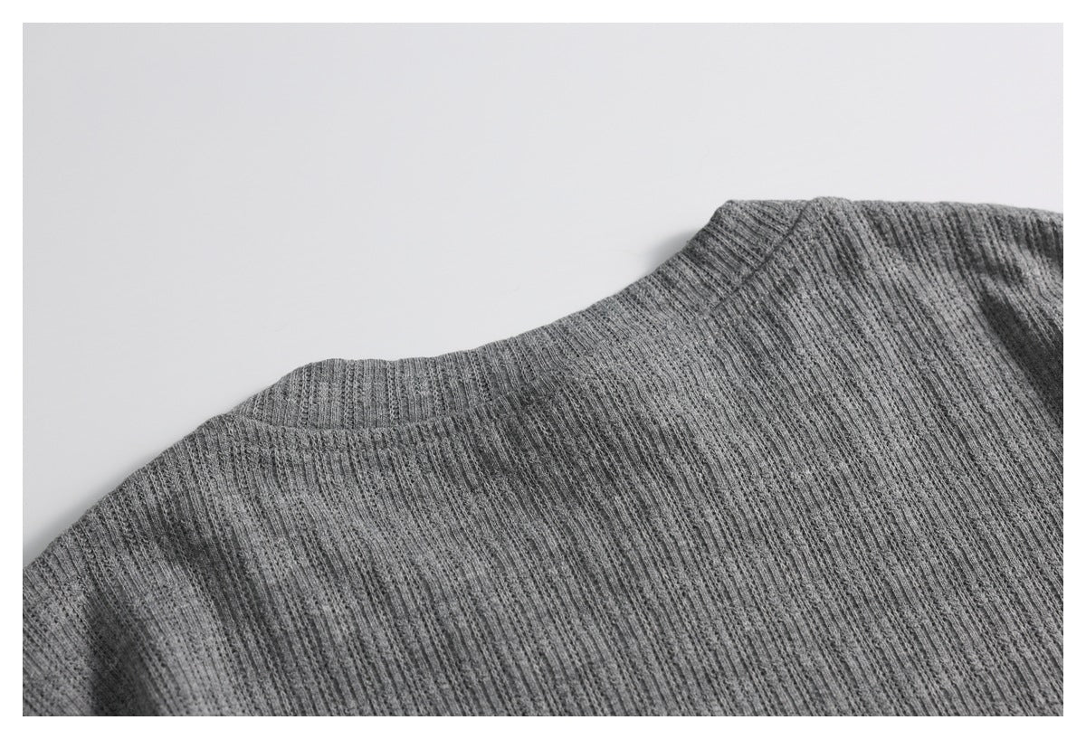 Close-up of the gray ribbed knit garment around its raised neckline and shoulder seam.