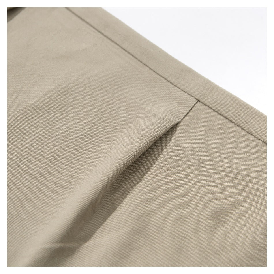 Close-up of beige trousers showing the slanted front pocket opening and stitching.